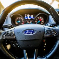 Detailed view of a car steering wheel and dashboard with illuminated controls.